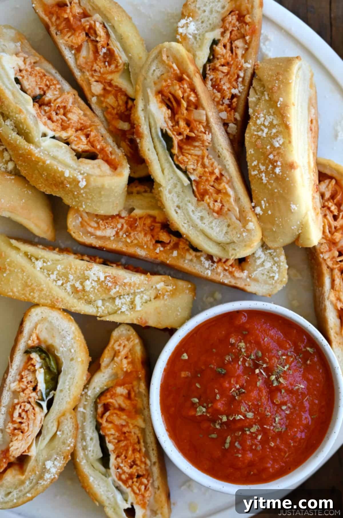 Perfectly baked slices of cheesy chicken Stromboli, ready to be enjoyed with marinara sauce.