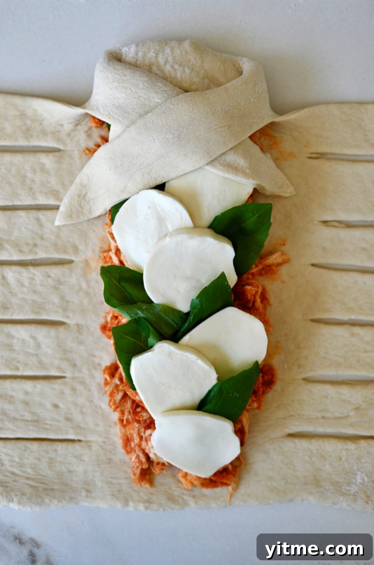 The beginning step to braiding pizza dough for a Stromboli - folding the top pizza dough over the filling. 