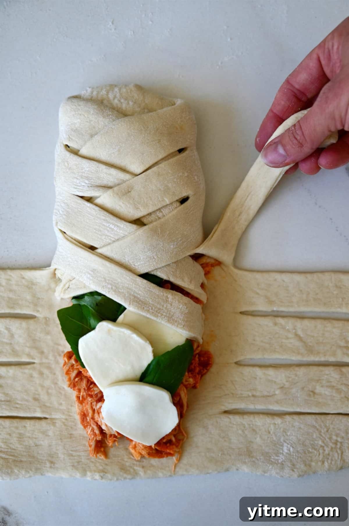 Pieces of pizza dough crisscrossed atop a cheesy chicken filling.