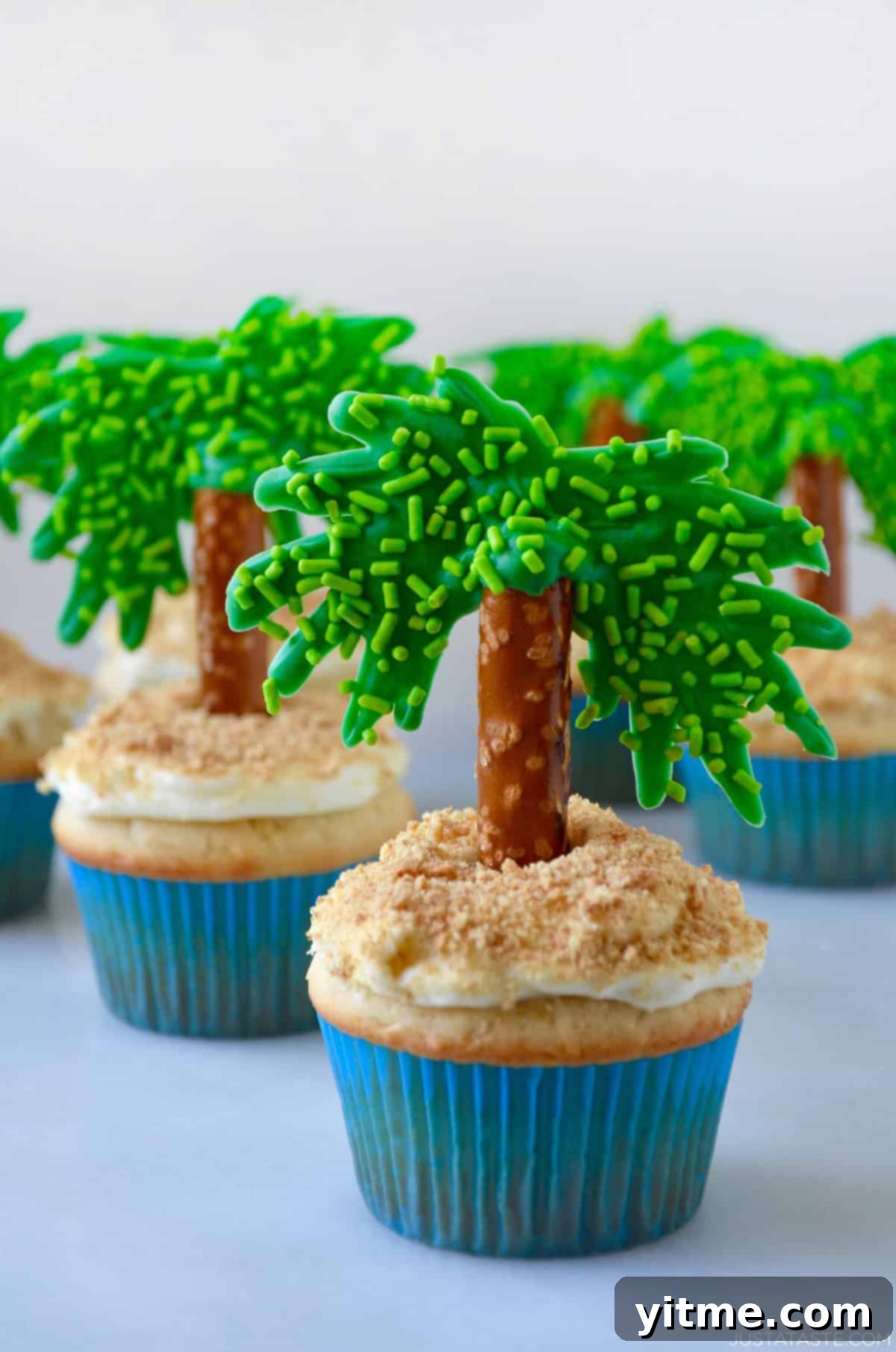 Coconut cupcakes with cream cheese frosting and pretzels with green candy melts for edible palm trees.