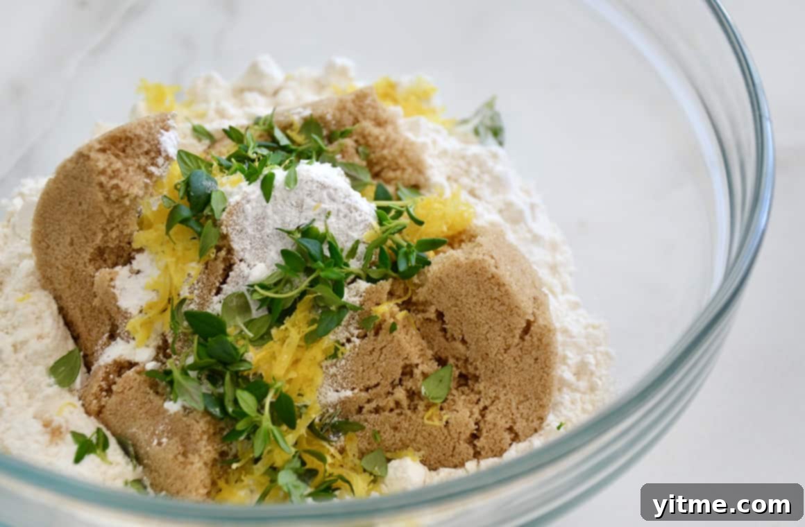 Ingredients for crumble topping: brown sugar, flour, thyme, and lemon zest in a glass bowl