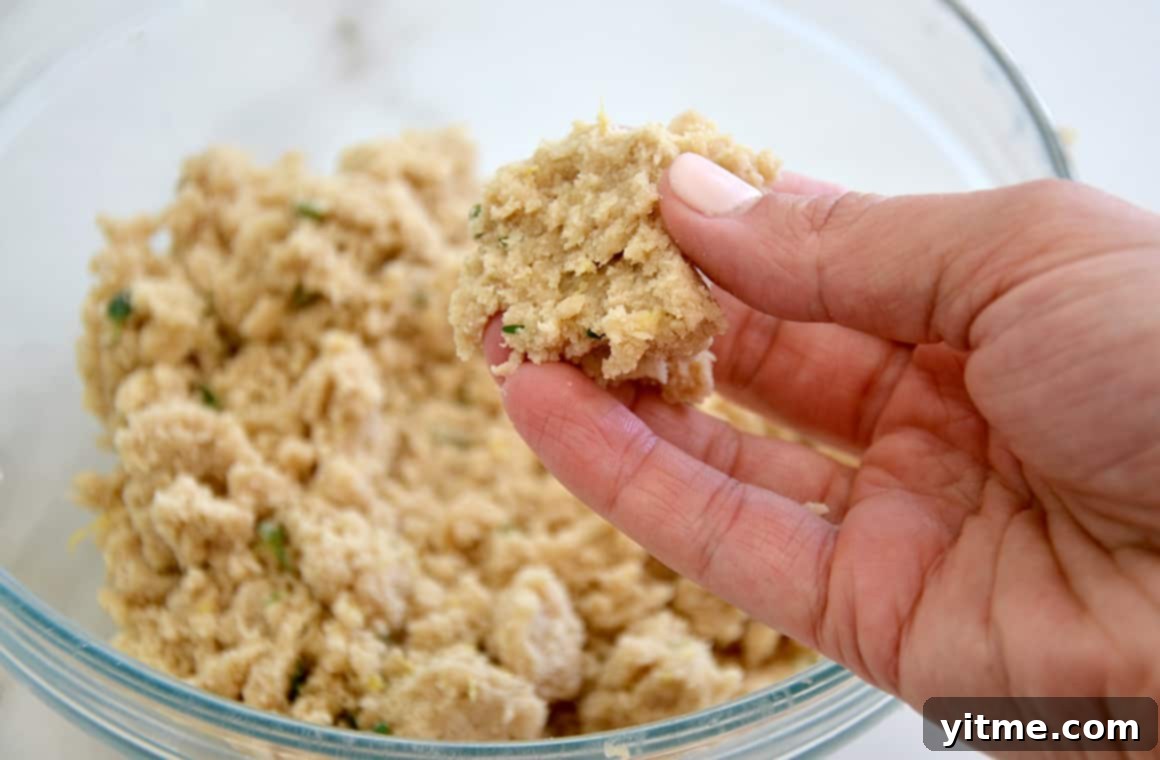 A hand pinching together flour and butter to form crumble topping