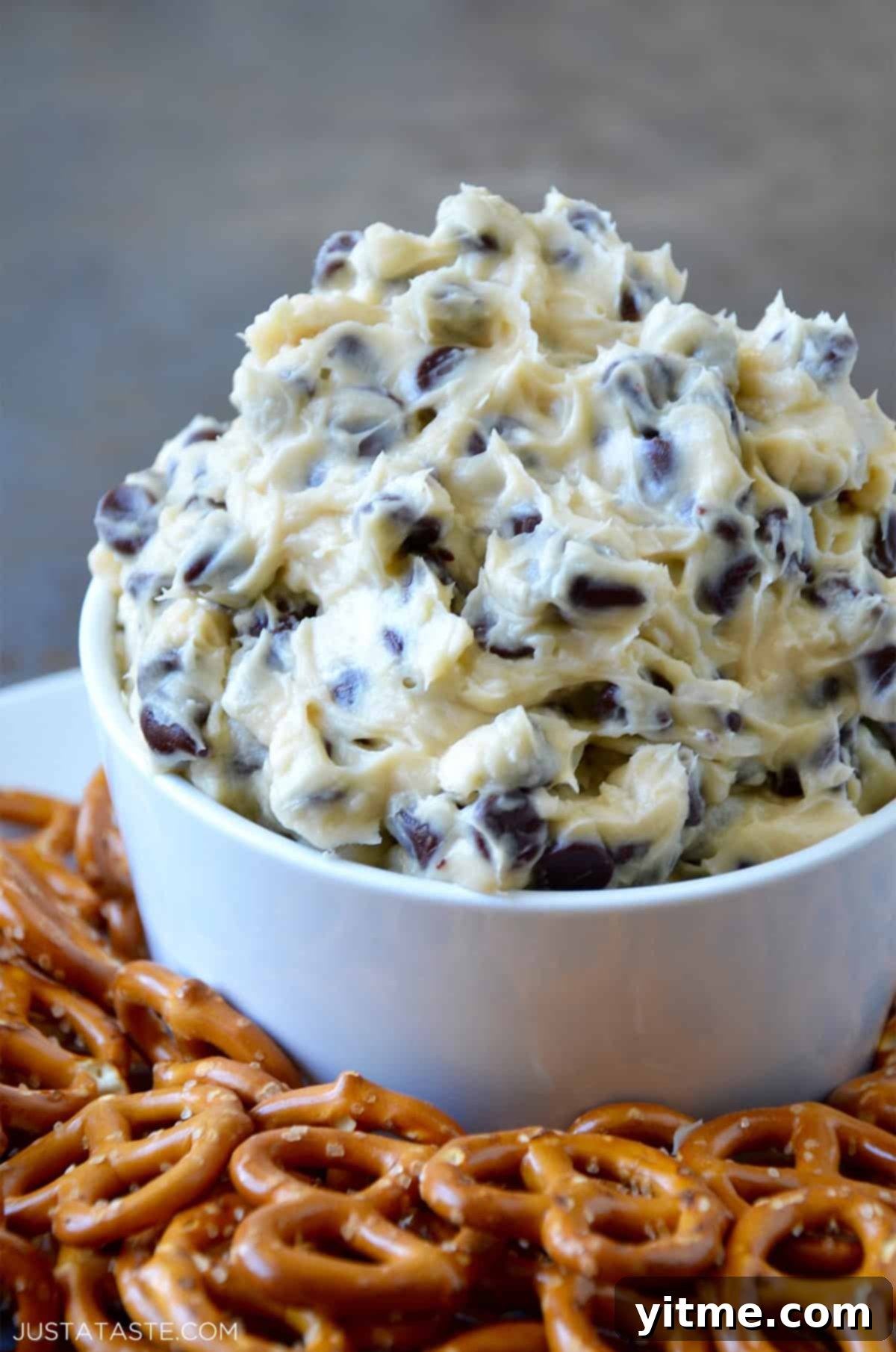 Chocolate Chip Cookie Dough Delight 7 Chocolate chip cookie dough dip in a white bowl surrounded by pretzels.