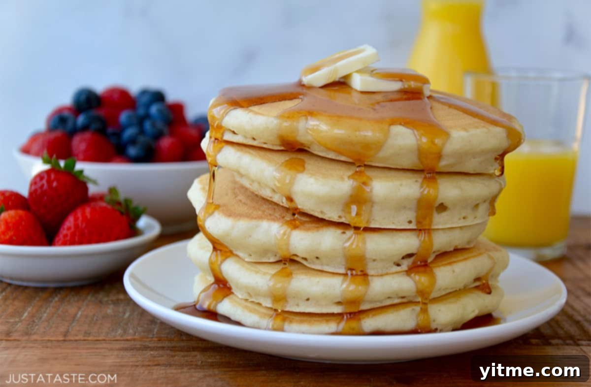 Stack of light and fluffy buttermilk pancakes topped with butter and maple syrup.
