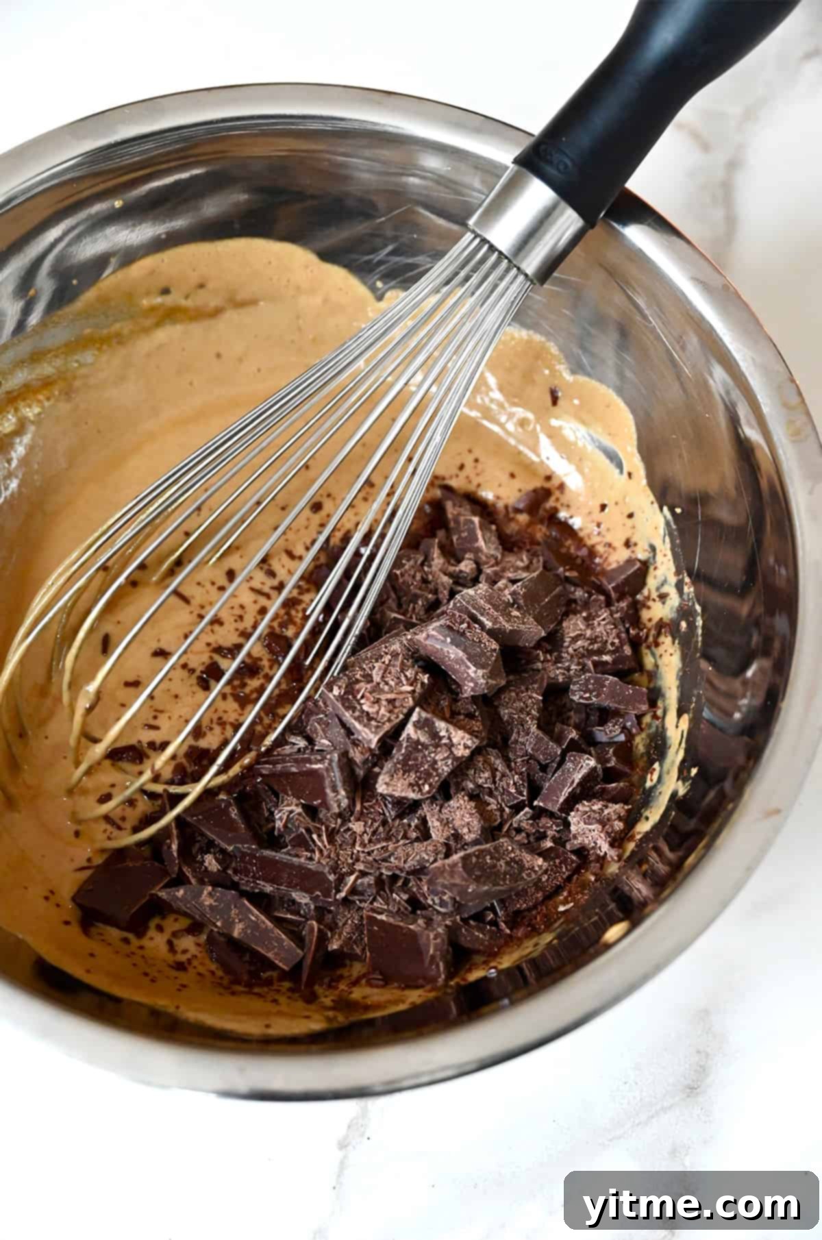 Chopped chocolate being whisked into egg yolk-espresso mixture.