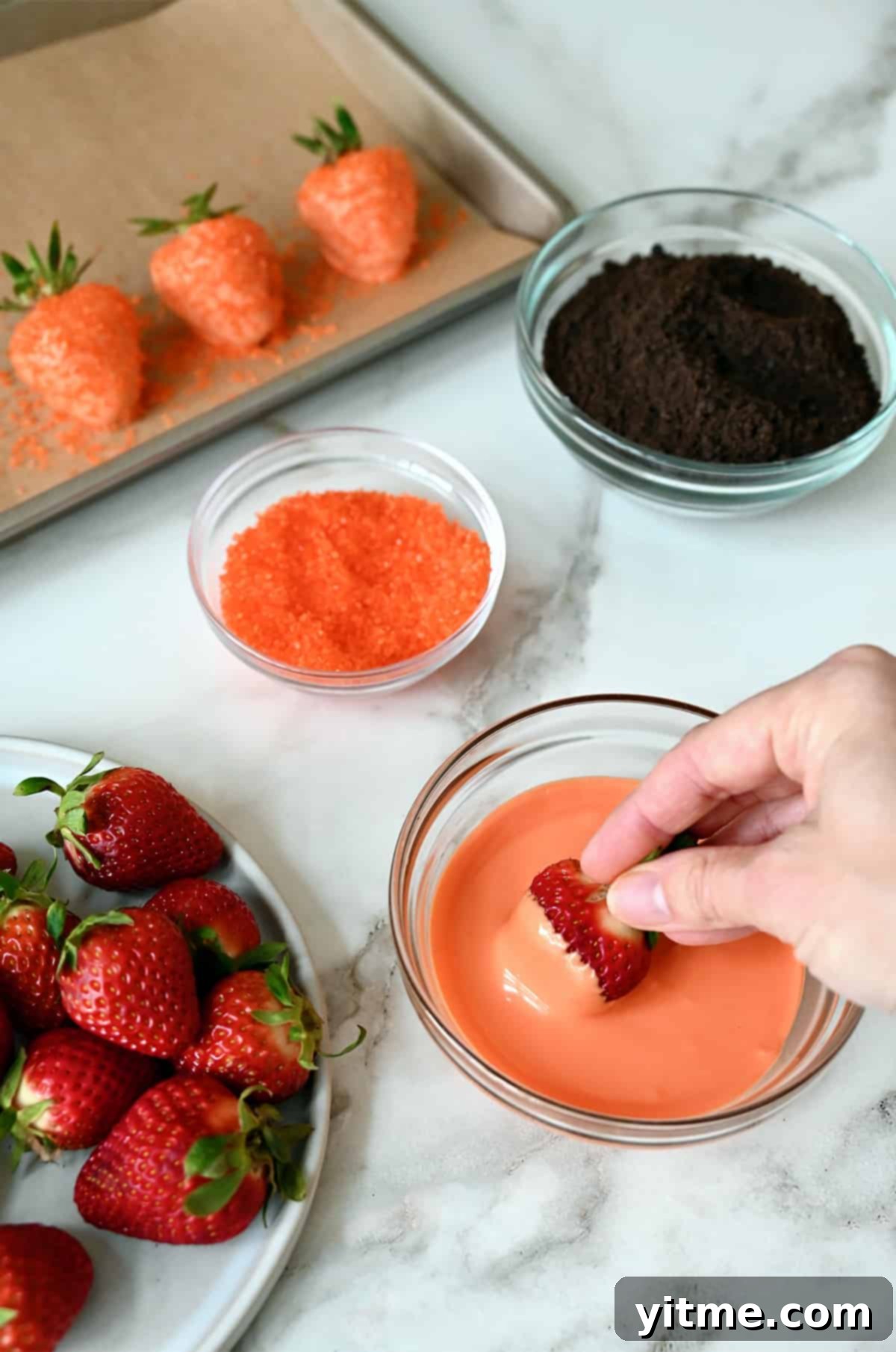 Dipping strawberries into melted orange candy melts.