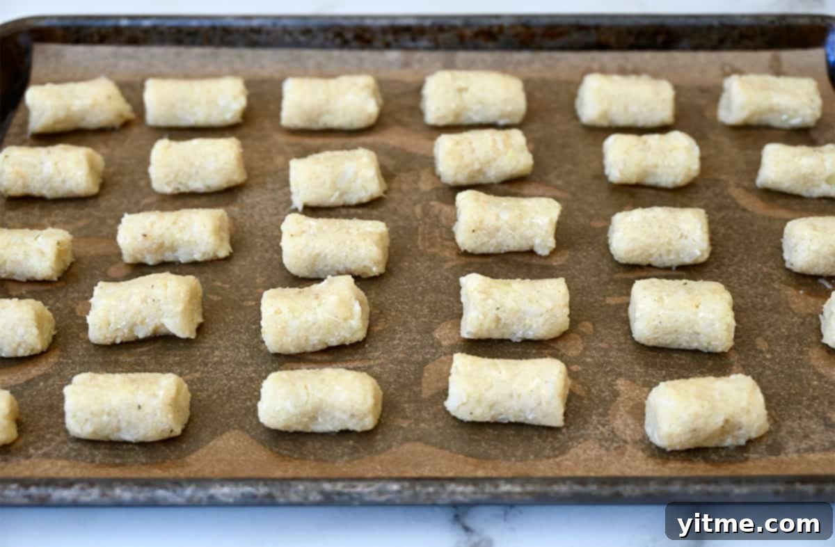 Cheesy Cauliflower Bites: 5 Ingredients, Endless Flavor 6 Unbaked cauliflower tots on a baking sheet.