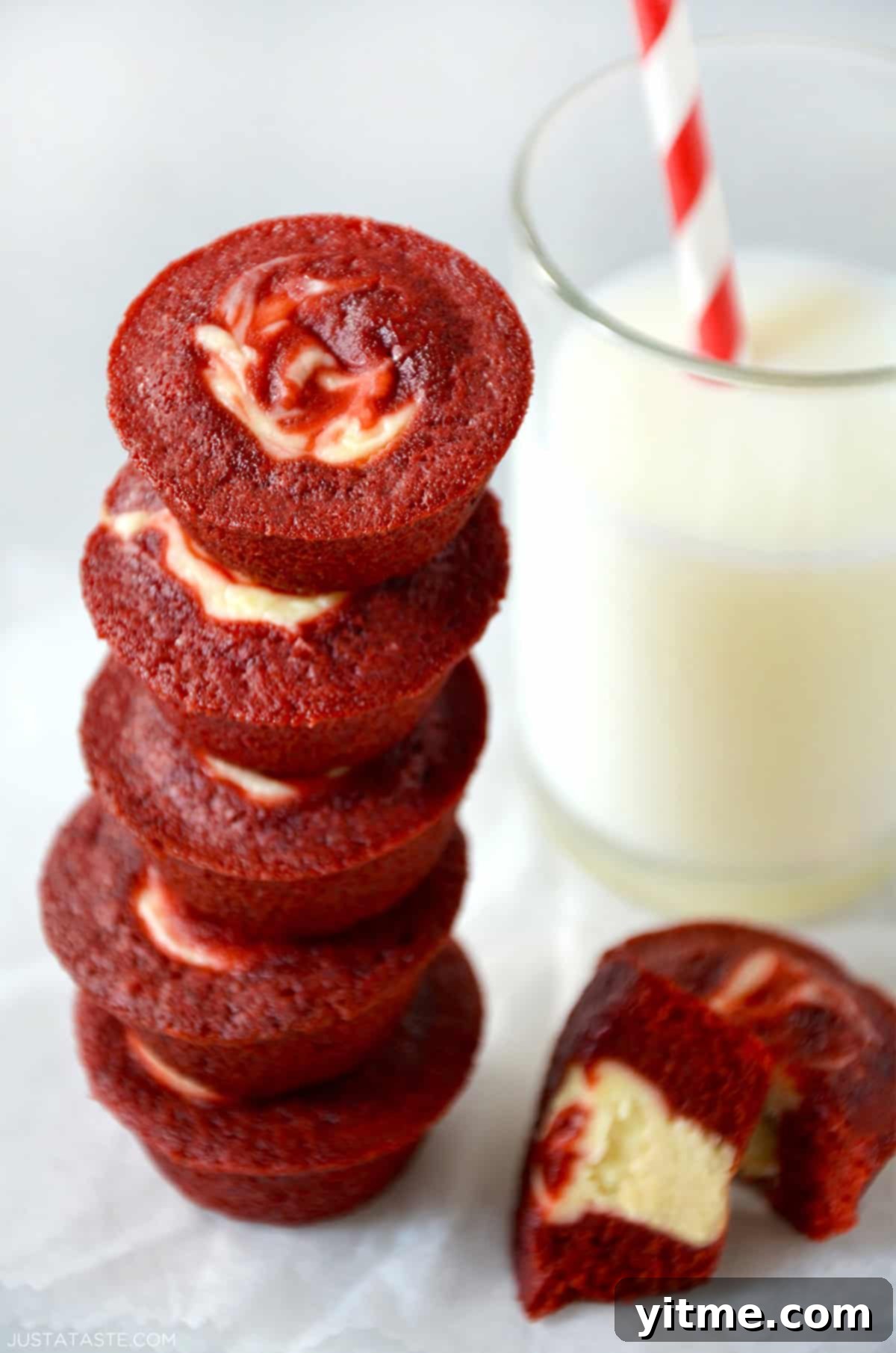 Red velvet cheesecake brownie bites stacked next to a glass of milk.
