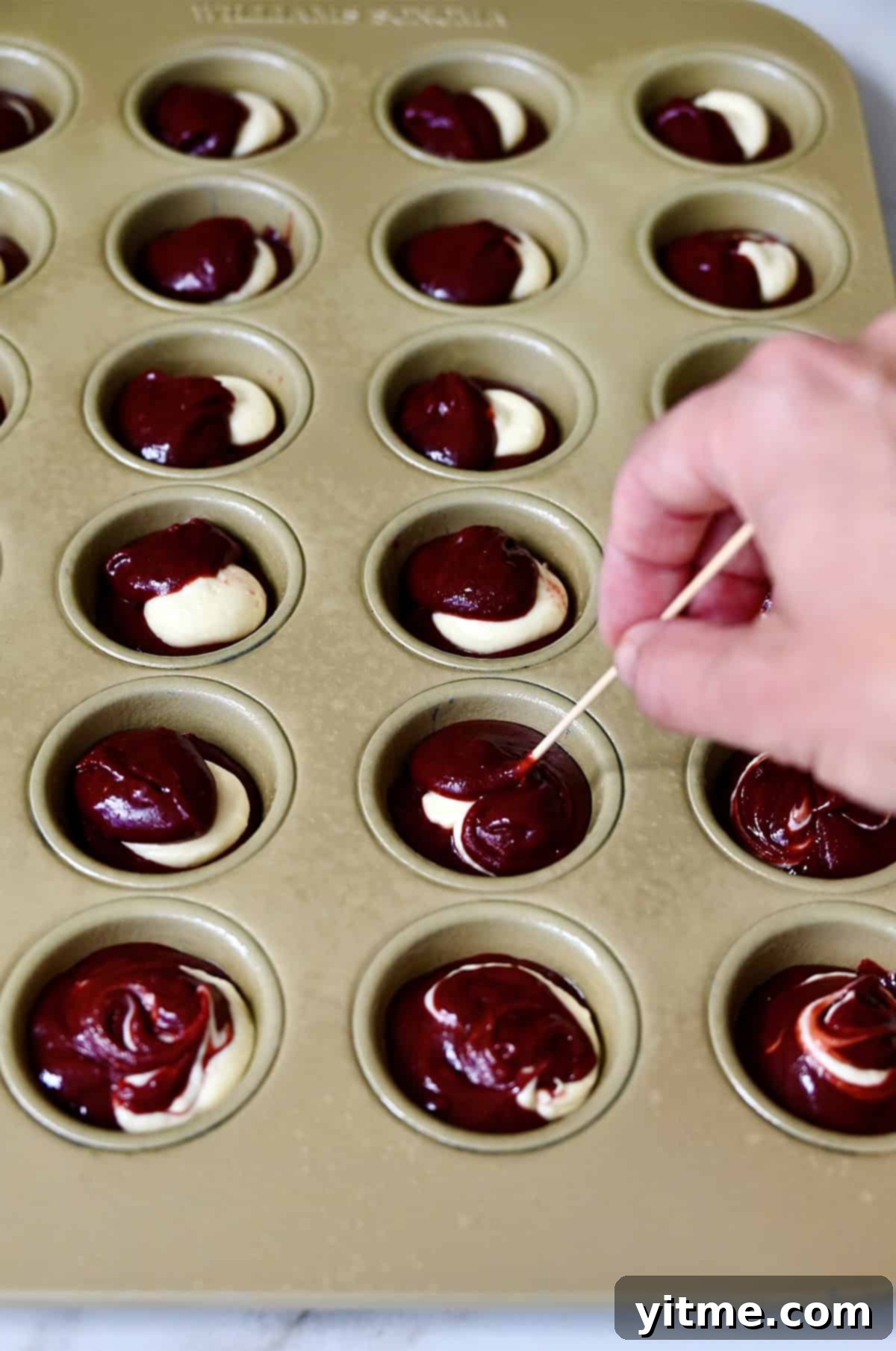 Swirling red velvet brownie batter with cheesecake filling.