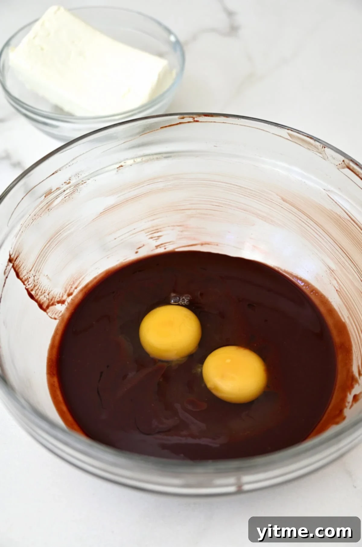 Eggs atop red velvet batter in a bowl.