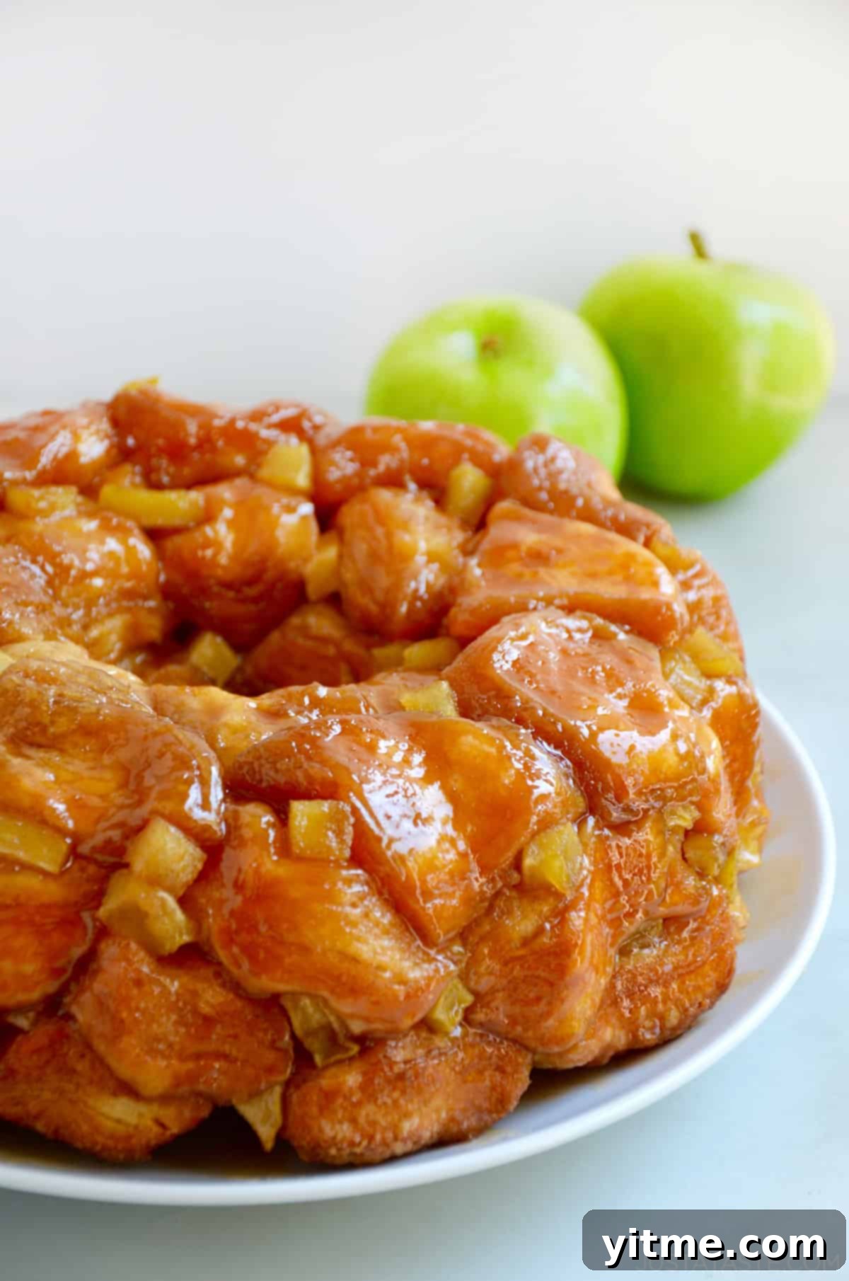 Caramel apple monkey bread with diced Granny Smith apples on a white serving plate.
