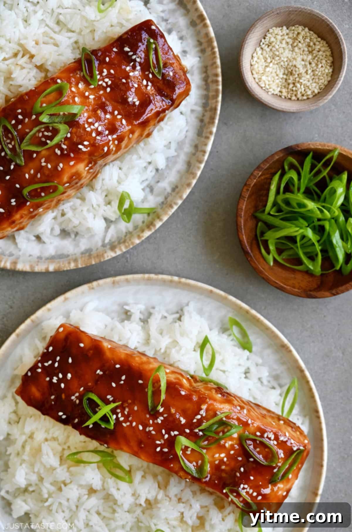 Honey-Garlic Glazed Salmon Delight 9 Two dinner plates with white rice and honey garlic salmon filets garnished with sesame seeds and chopped scallions.