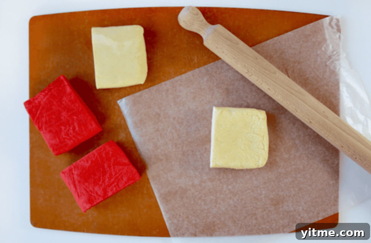 Four perfectly rolled rectangles of dough, two vibrant red and two pure white, neatly arranged on a cutting board. A rolling pin rests beside a sheet of white dough, ready for the next step of layering to create festive pinwheel cookies.