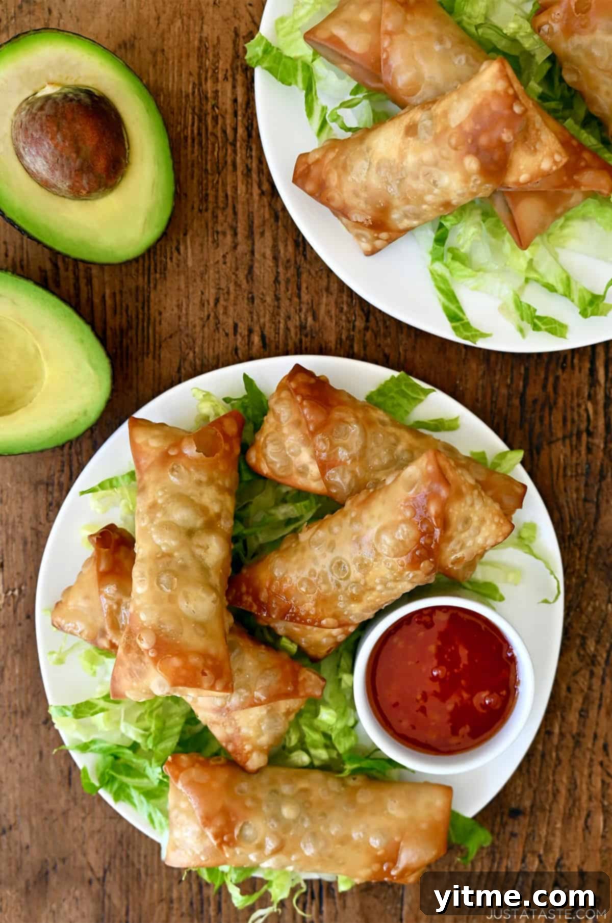 Crispy Avocado egg rolls served on a bed of shredded lettuce with a side of sweet chili dipping sauce.
