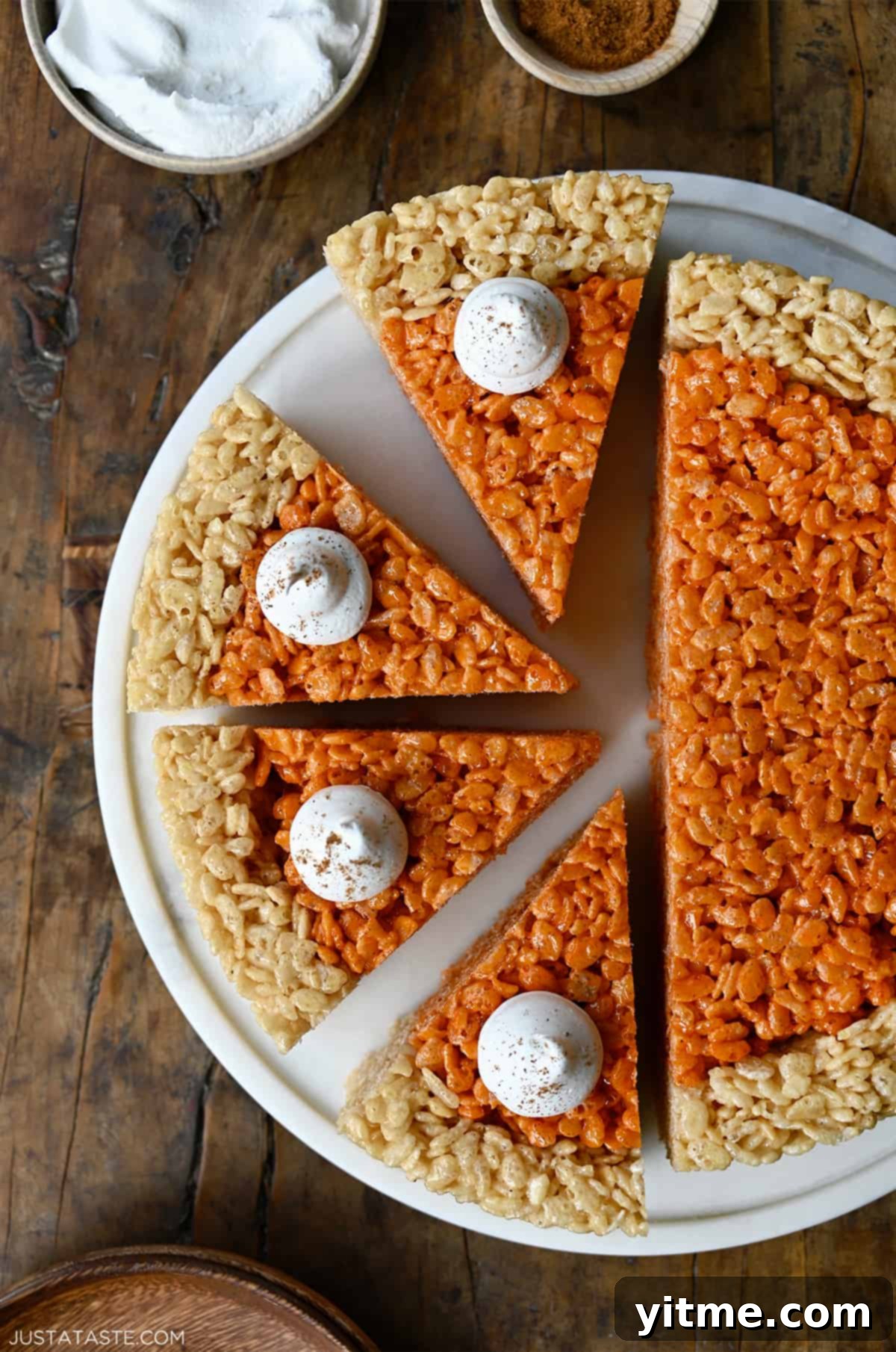 Pumpkin Spice Rice Krispies Delights 2 Pumpkin Rice Krispie treats cut into pie wedges and topped with whipped cream.