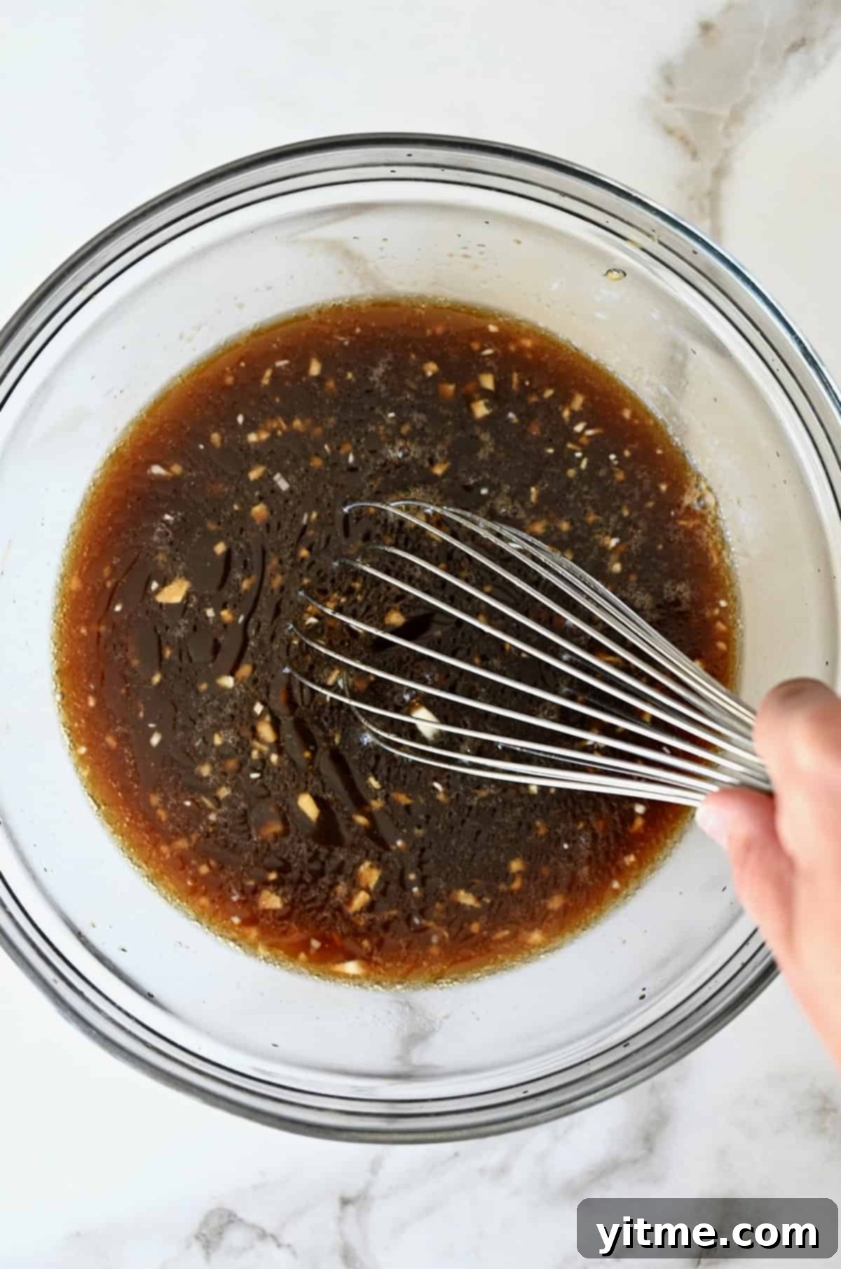 Homemade teriyaki sauce being whisked together in a glass bowl.