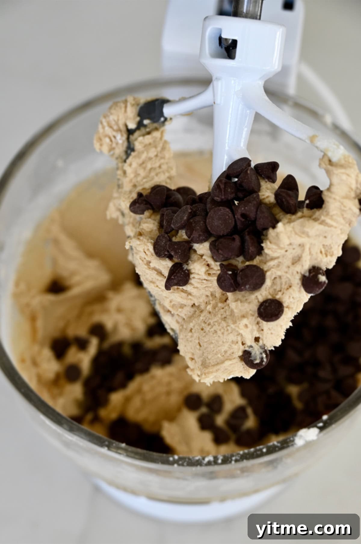 Caramel Lava Chocolate Chip Cookies 5 Chocolate chip cookie dough covering the paddle attachment of a stand mixer.