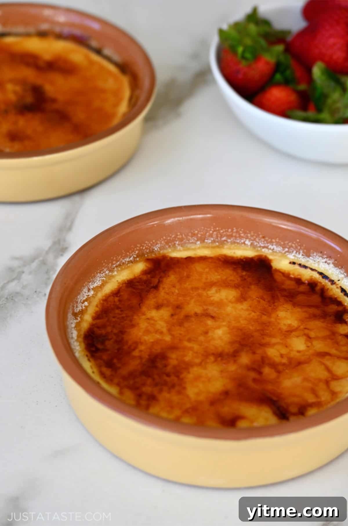 Two ramekins containing creme brulee cheesecakes with a burnt sugar topping.