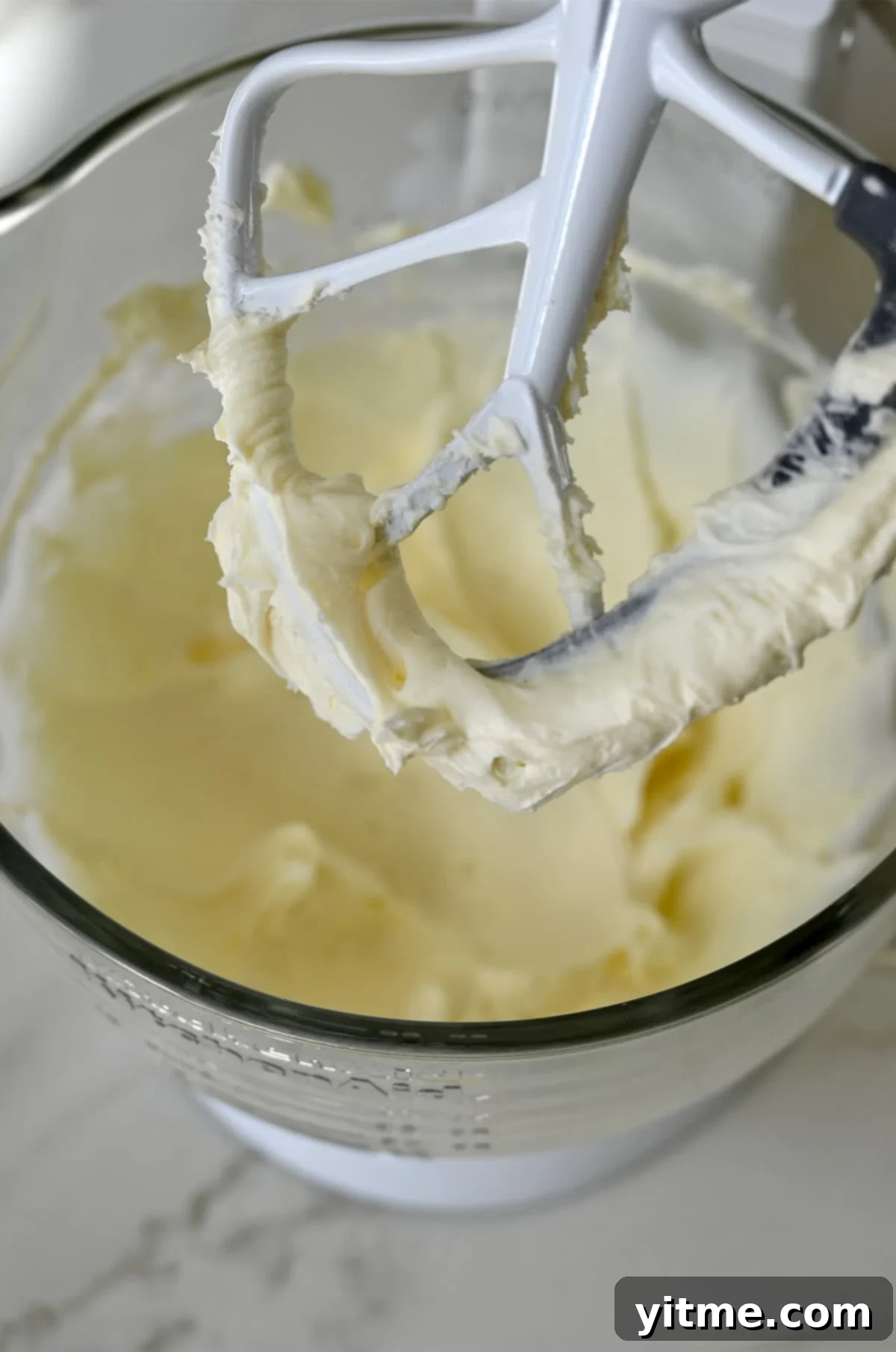 Beaten cream cheese in a stand mixer bowl with the paddle attachment.