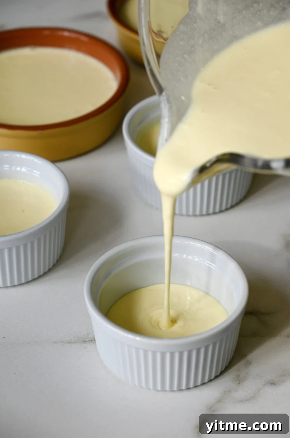 Pouring custard into small ramekins to bake.