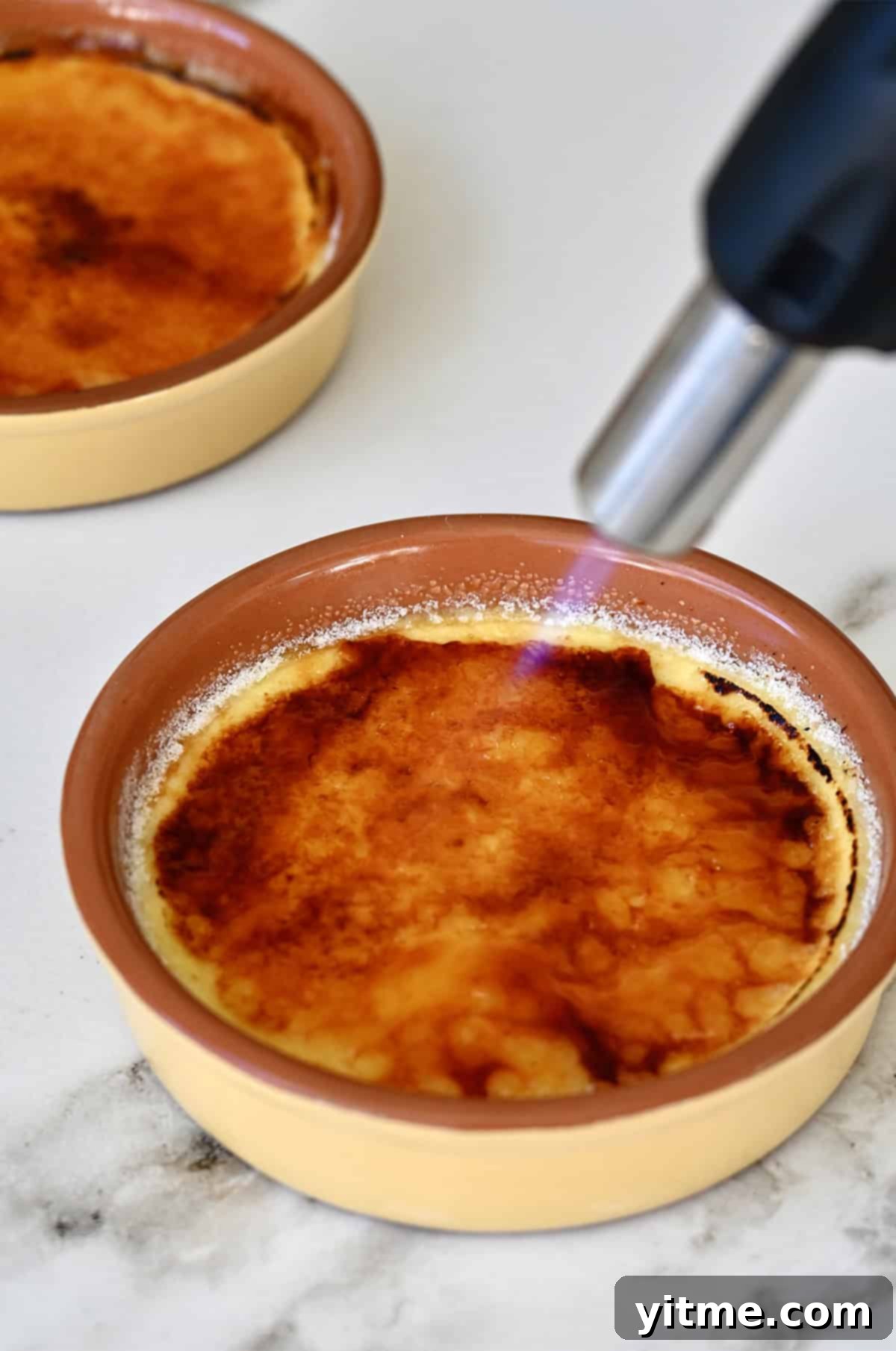 Torching sugar atop a crème brûlée to create that signature caramelized topping.