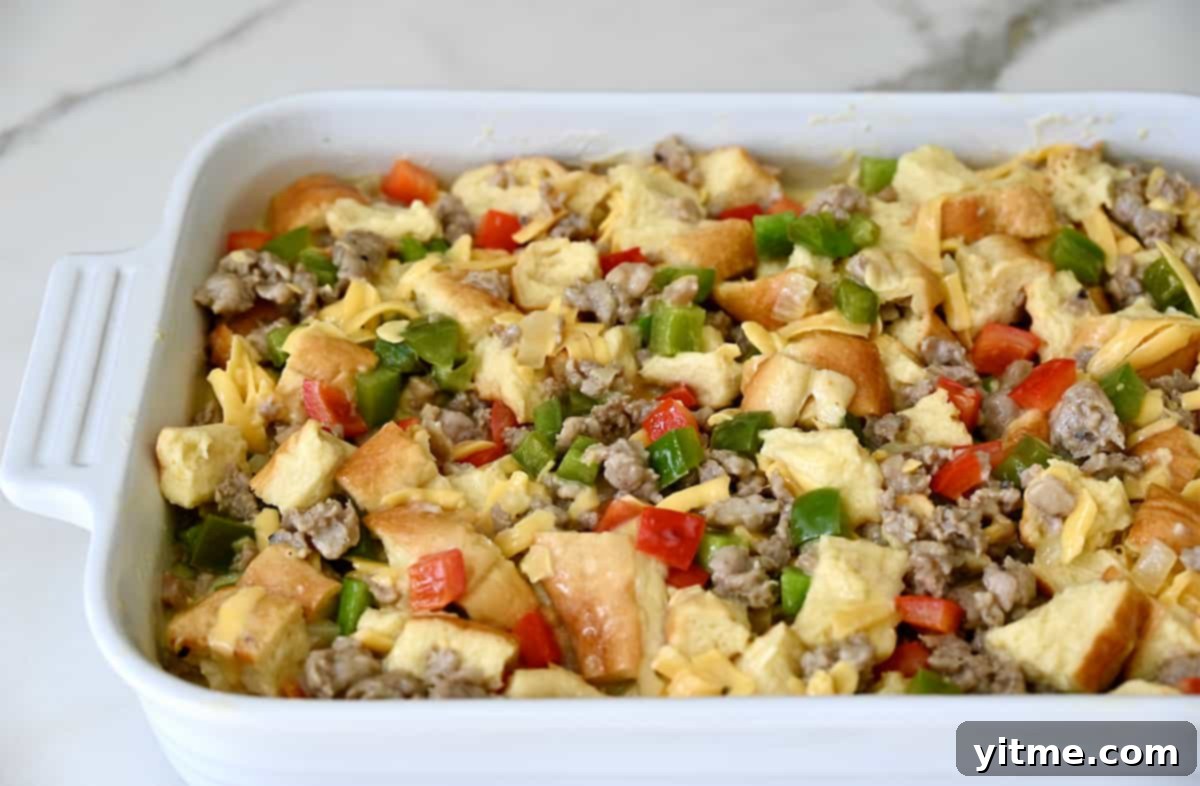 Sausage Sunrise Strata 4 Egg mixture with bread, sausage, and peppers in a baking dish