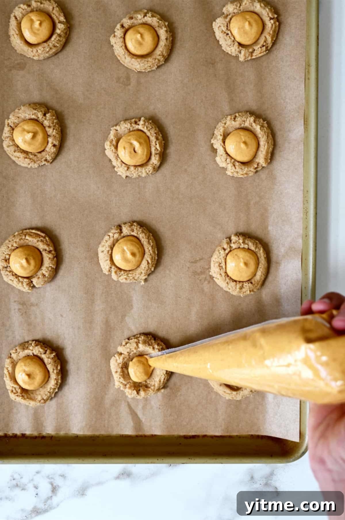 Piping pumpkin cheesecake filling into the center of cookie dough.