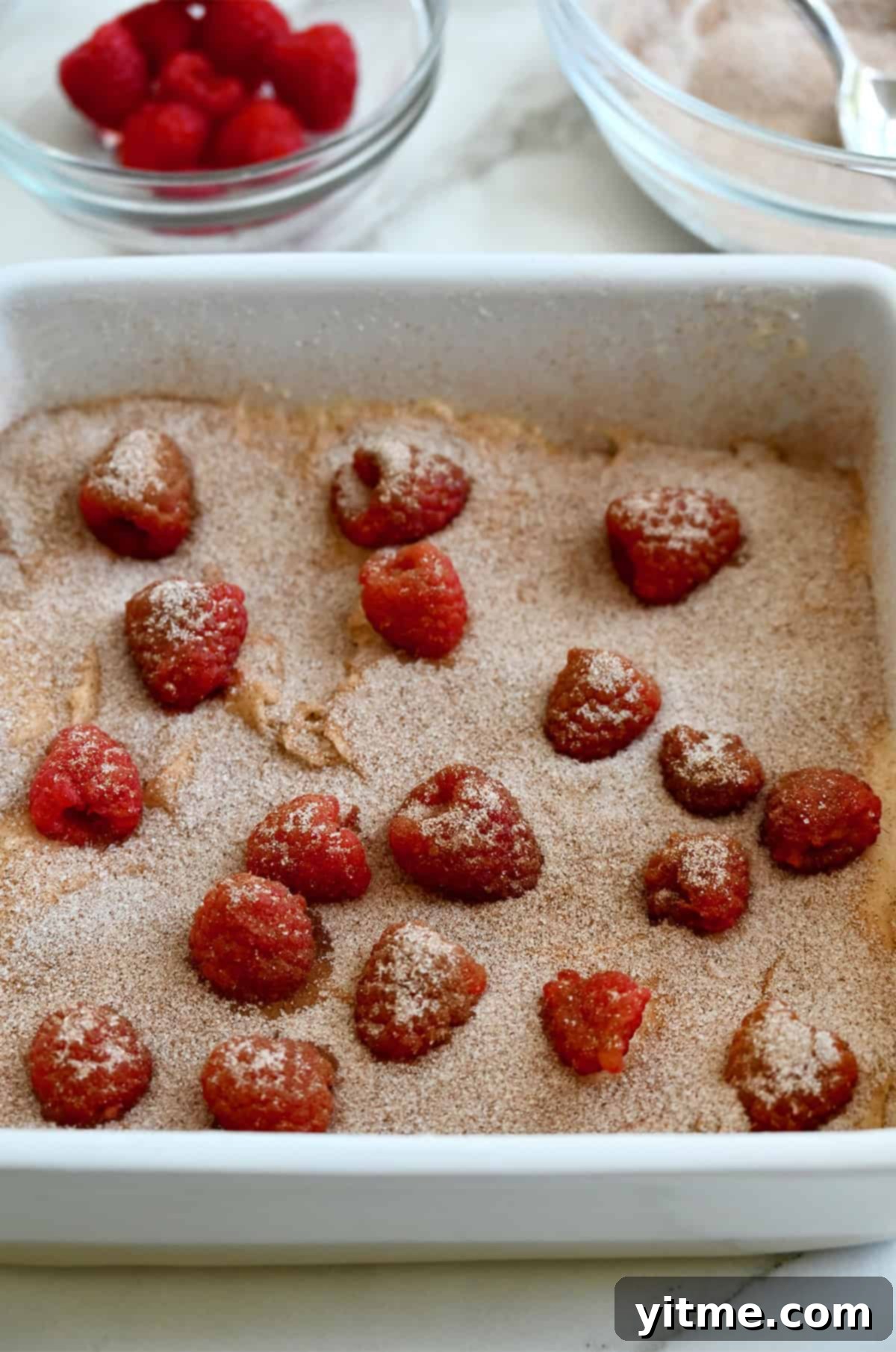 The first layer of coffee bake batter sprinkled with cinnamon sugar and fresh raspberries. 