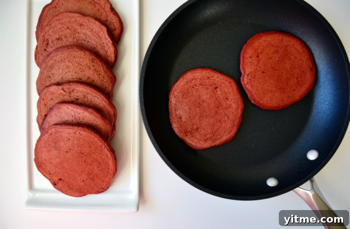 Red velvet pancakes cooking in a skillet