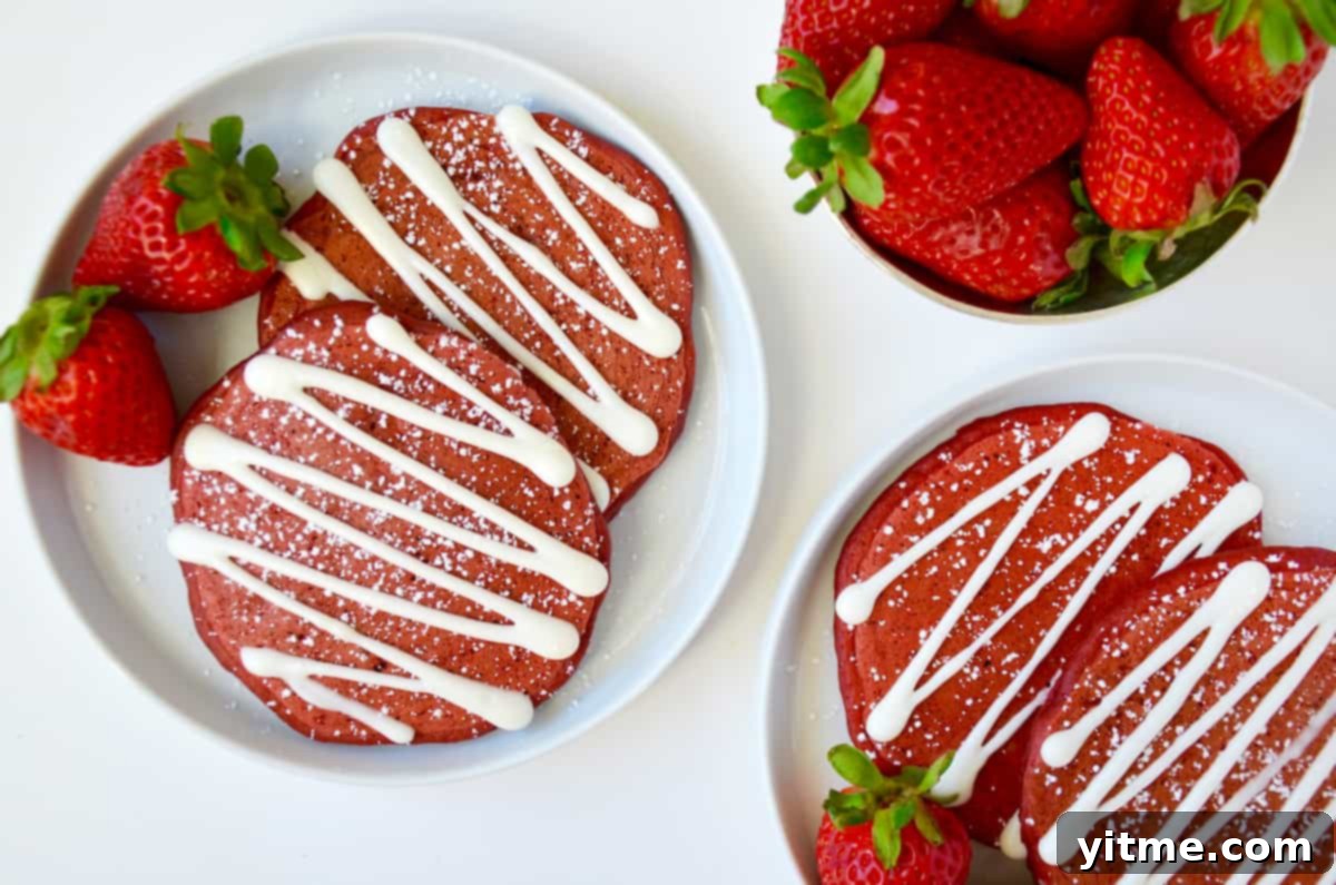 Red velvet pancakes plated with strawberries and powdered sugar
