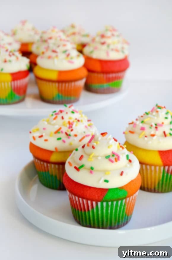 Rainbow Cupcakes with Buttercream Frosting and sprinkles on white plate