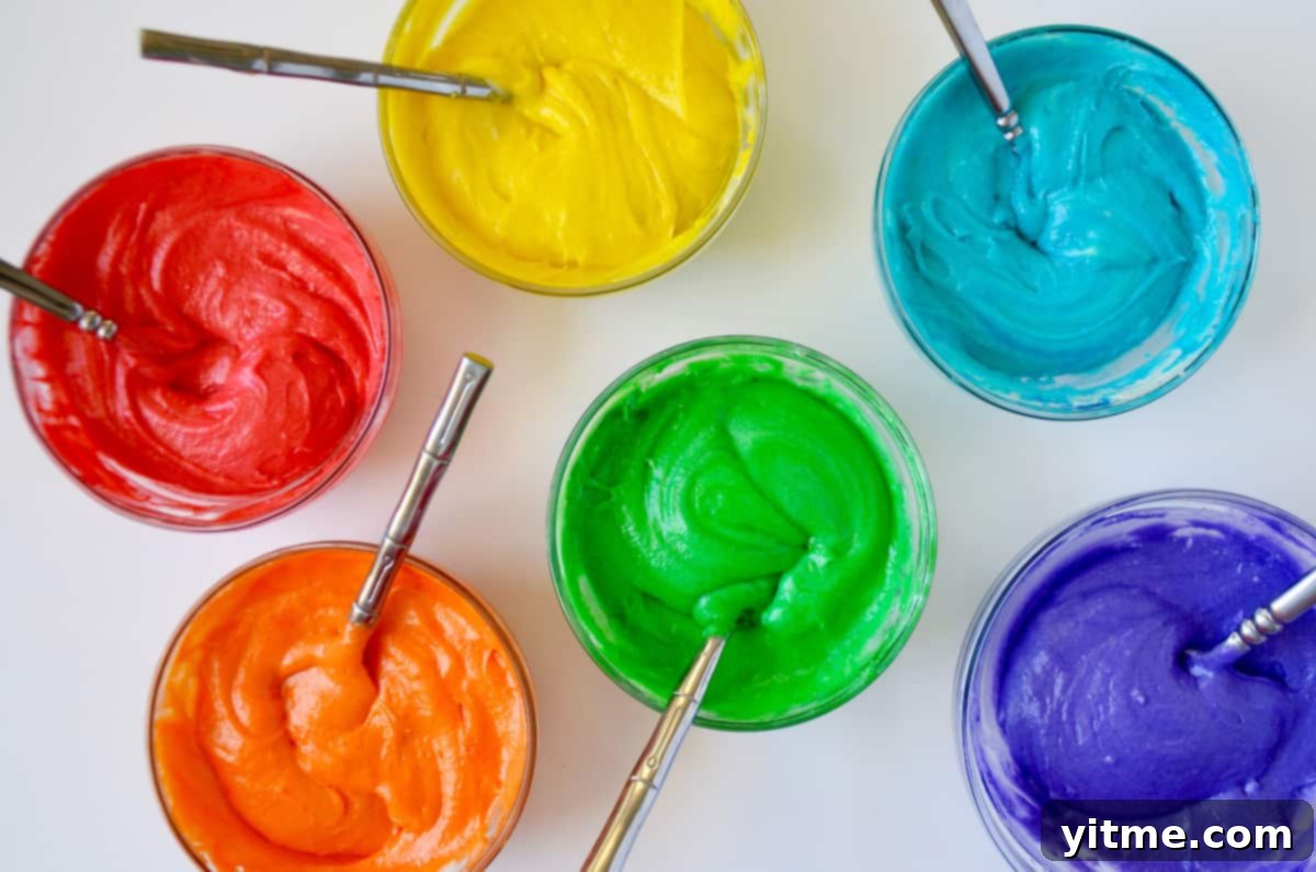 Six bowls of cupcake batter tinted with rainbow colors