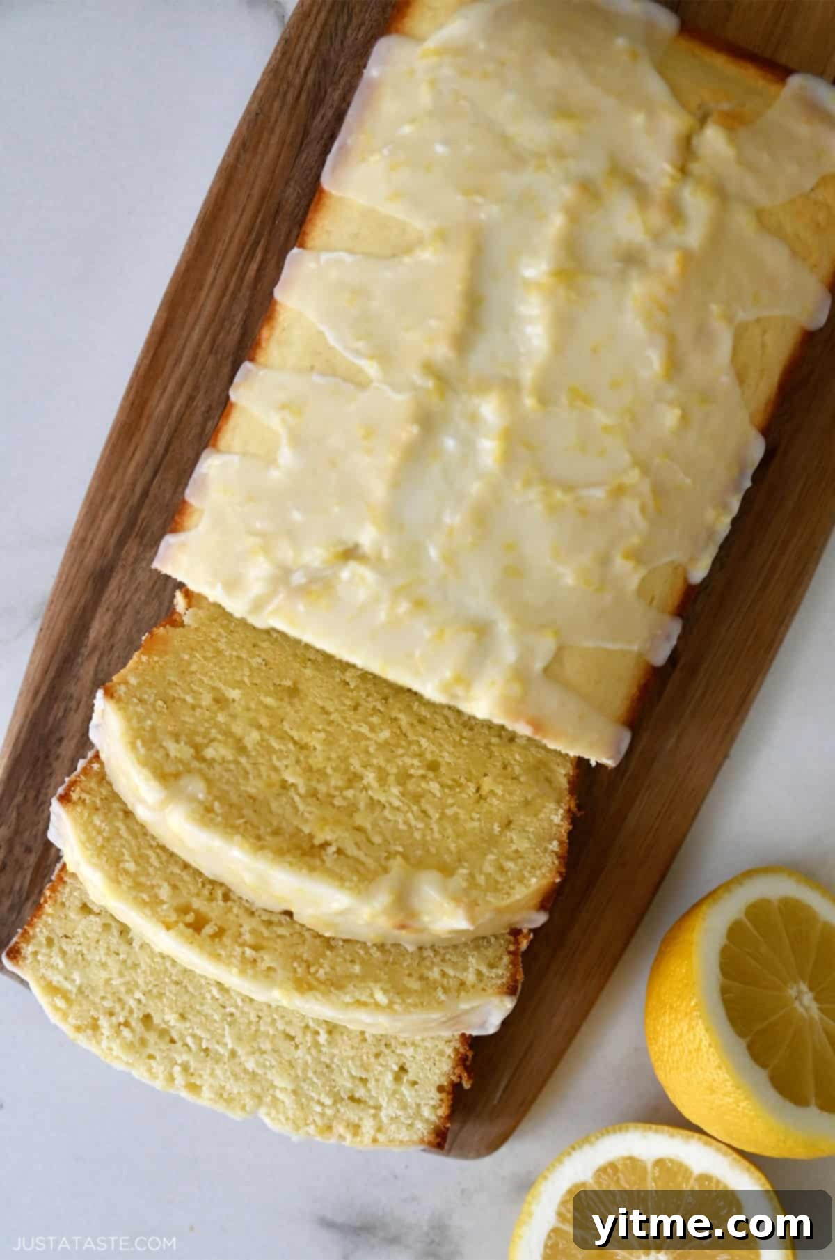 Several slices of glazed lemon bread beautifully arranged on a rustic wood cutting board, showcasing its moist texture.