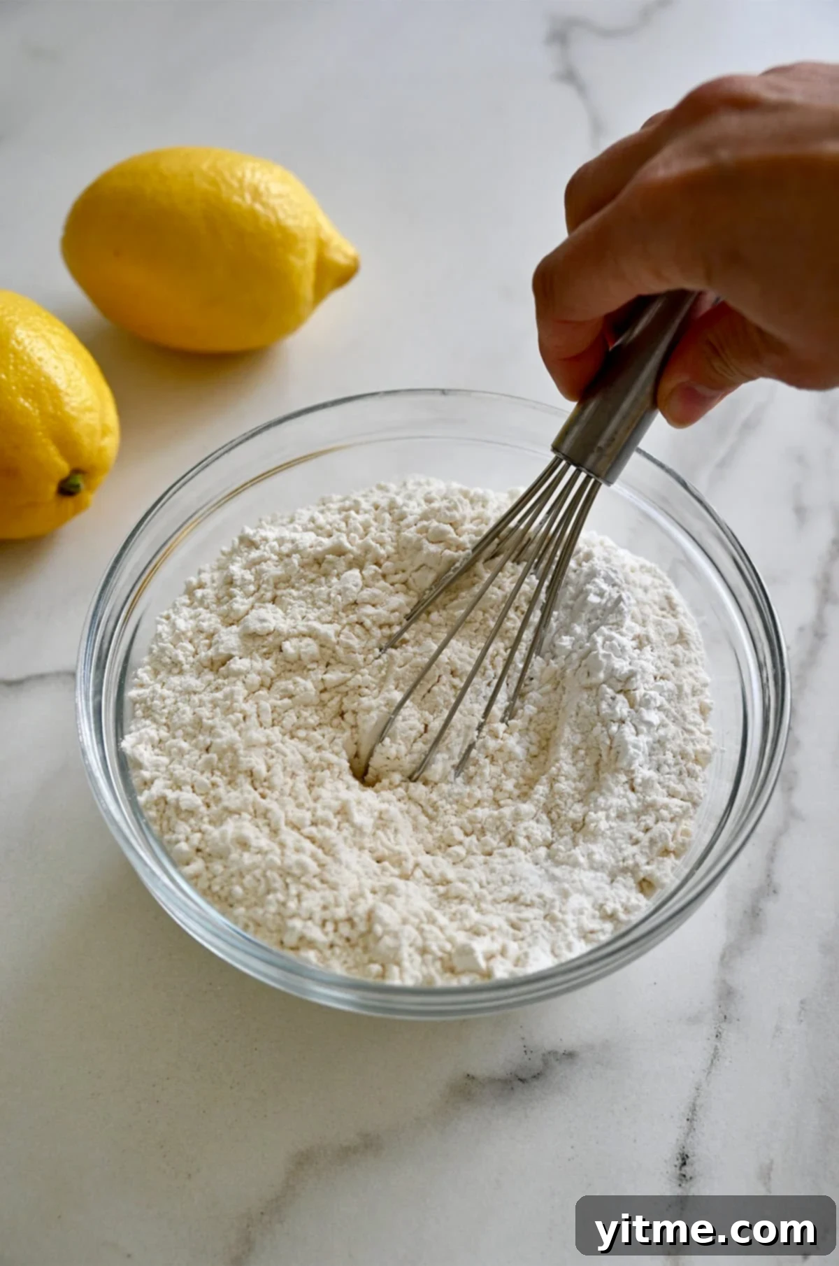 A small bowl containing whisked dry ingredients: flour, baking powder, and salt.