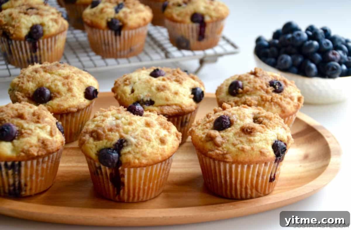 Crumb-Topped Blueberry Muffins 6 Blueberry crumble muffins on a wood serving plate.