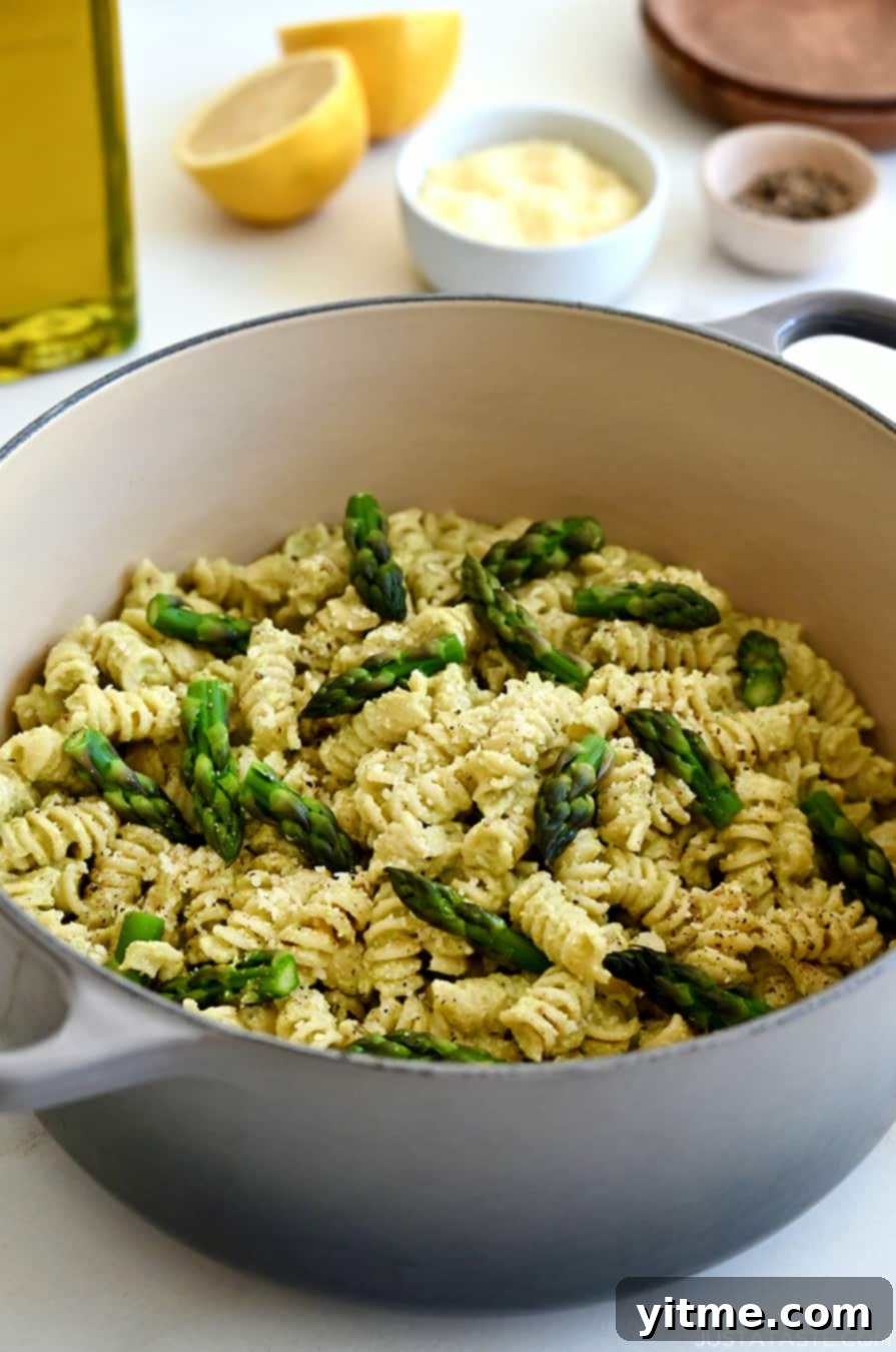 A large stockpot containing Cheesy Asparagus Pesto Pasta with fresh asparagus pieces