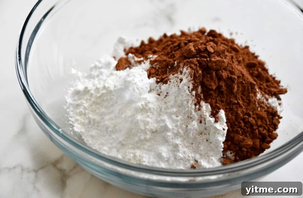 A clear bowl containing cocoa powder and powdered sugar