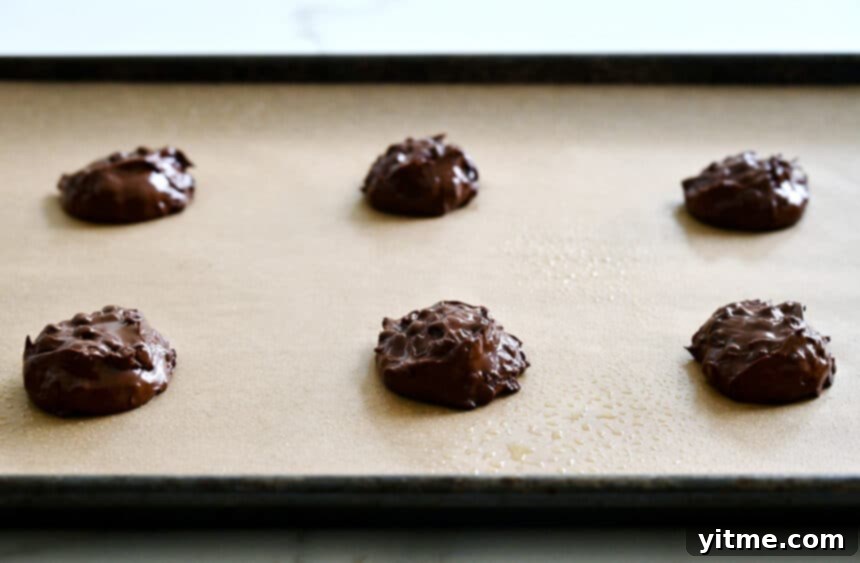 Unbaked scoops of dough atop a parchment paper-lined baking sheet