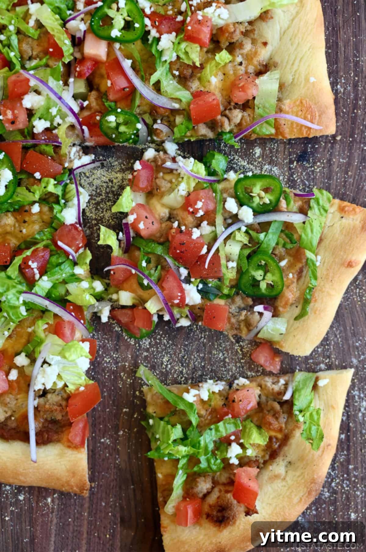 Cheesy taco pizza topped with refried beans, shredded lettuce, jalapeños, cojita cheese and diced tomatoes.