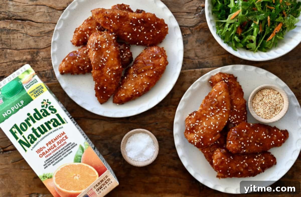 Citrus Glazed Baked Chicken Strips 8 Two plates containing orange chicken tenders topped with sesame seeds next to a carton of Florida's Natural Orange Juice, ready to be enjoyed.