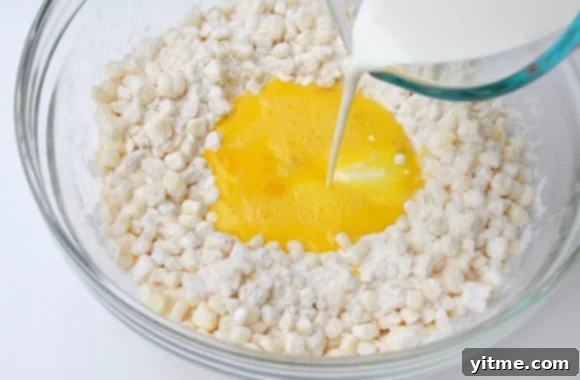 Heavy cream being poured into Quick and Easy Corn Fritters batter