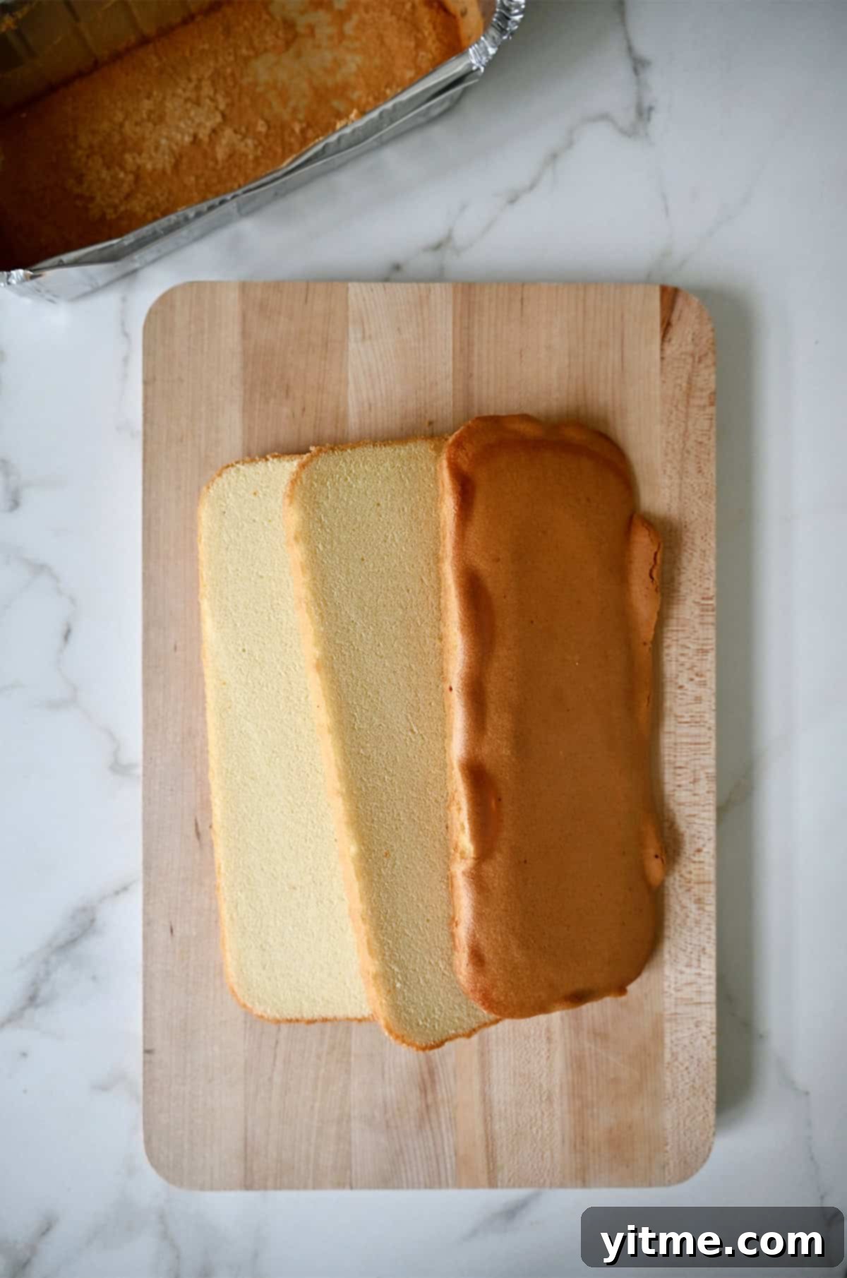 Pound cake cut into three equal slices on a cutting board.