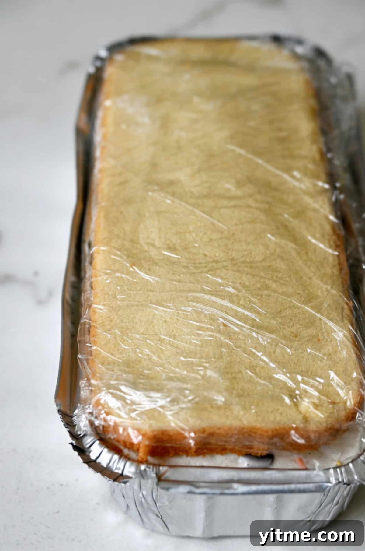 Sara Lee pound cake ice cream cake tightly wrapped in plastic wrap.