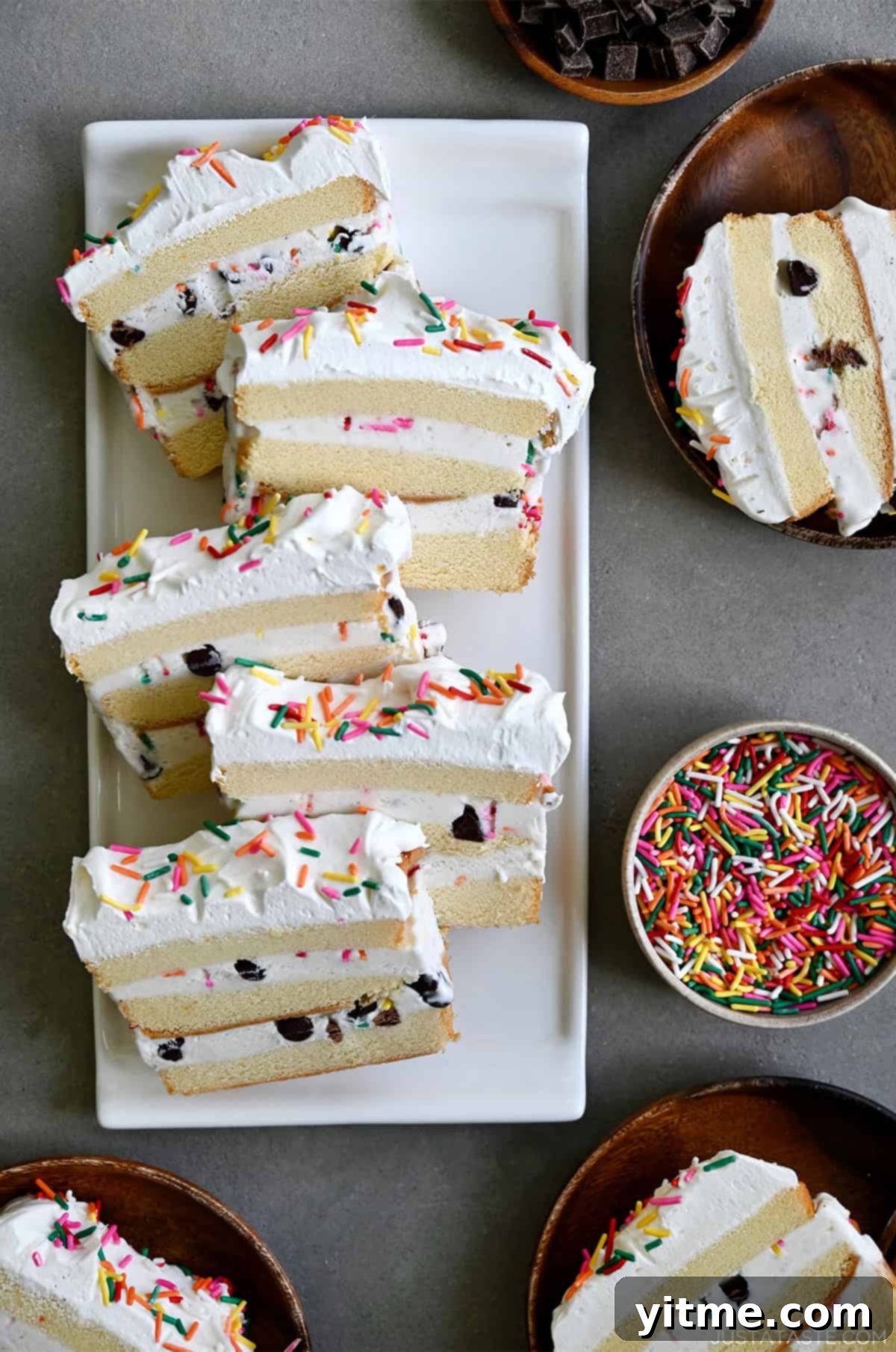 Slices of easy ice cream cake made with layers of Sara Lee pound cake, vanilla ice cream, chocolate chips and sprinkles on a white serving platter.