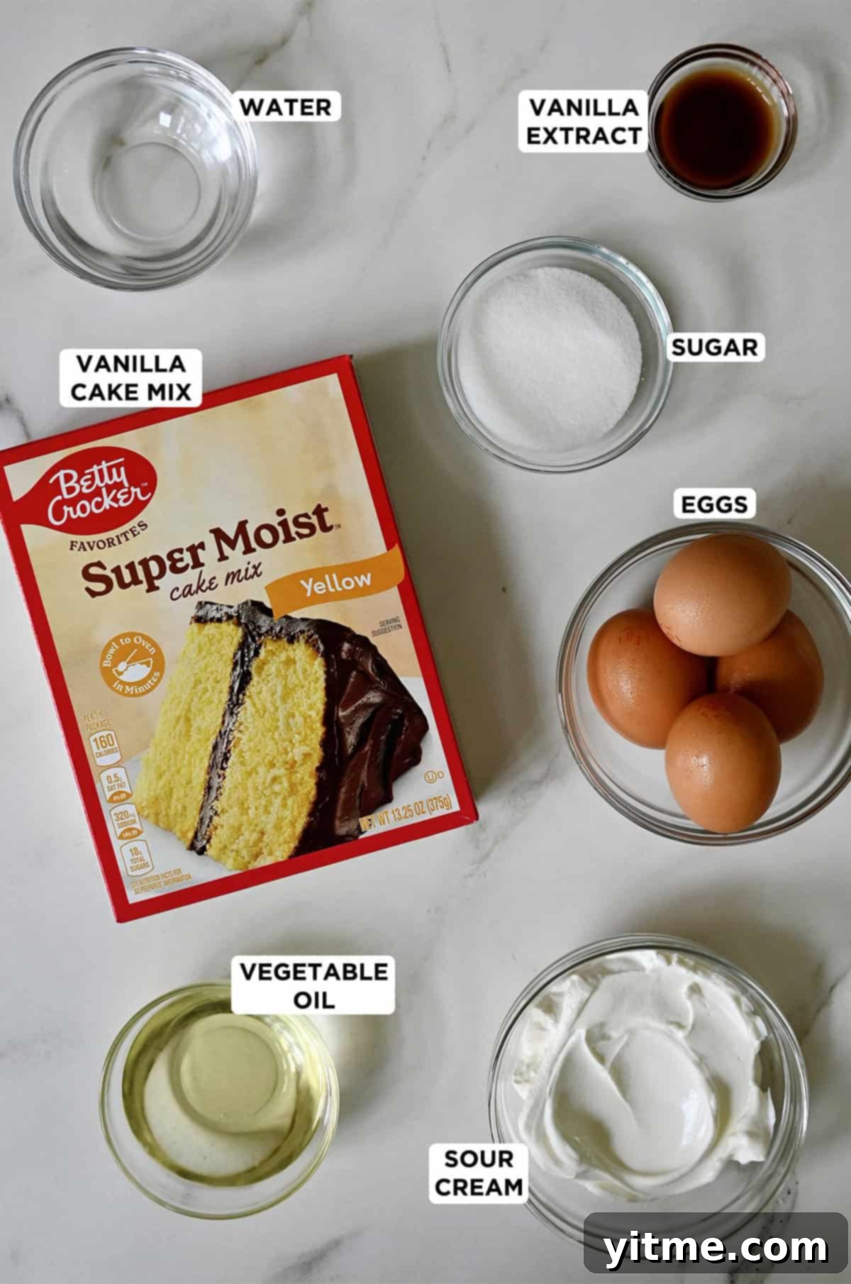 Cake mix cupcakes ingredients, including a yellow Betty Crocker cake mix, sugar, eggs, sour cream, vegetable oil, vanilla extract and water.