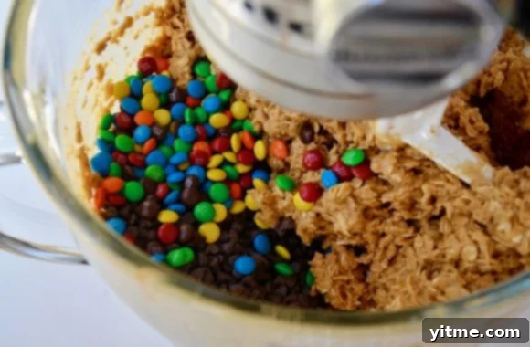 Stand mixer bowl with monster cookies batter, mini chocolate chips and M&Ms