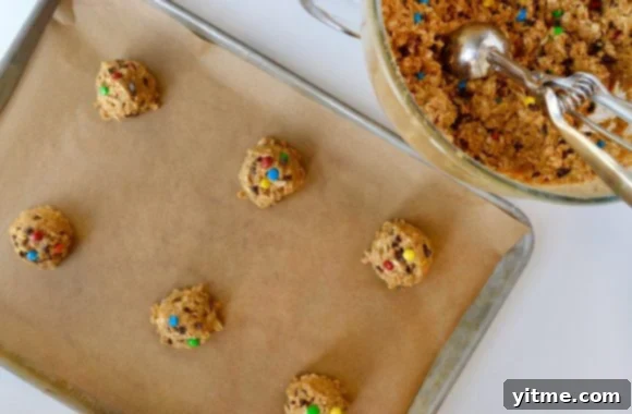 Unbaked cookies on baking sheet with cookie scoop