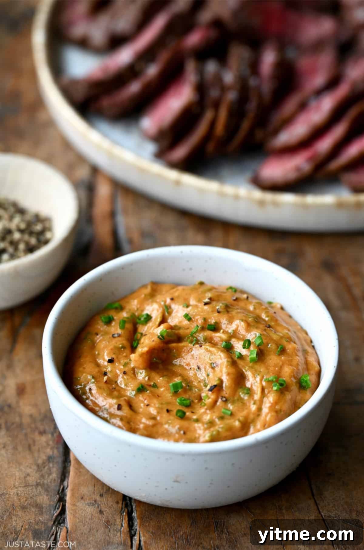 A small white bowl containing homemade cowboy butter garnished with chopped chives.