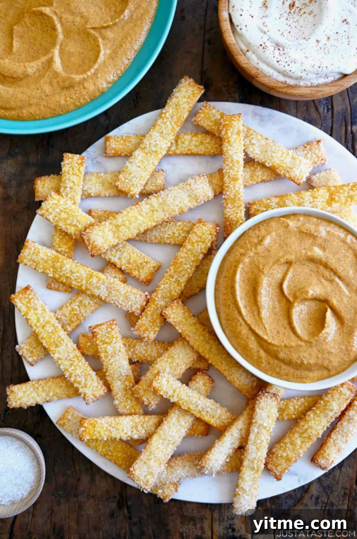Fluffy pumpkin pie dip in a bowl on a plate loaded with pie crust "fries."