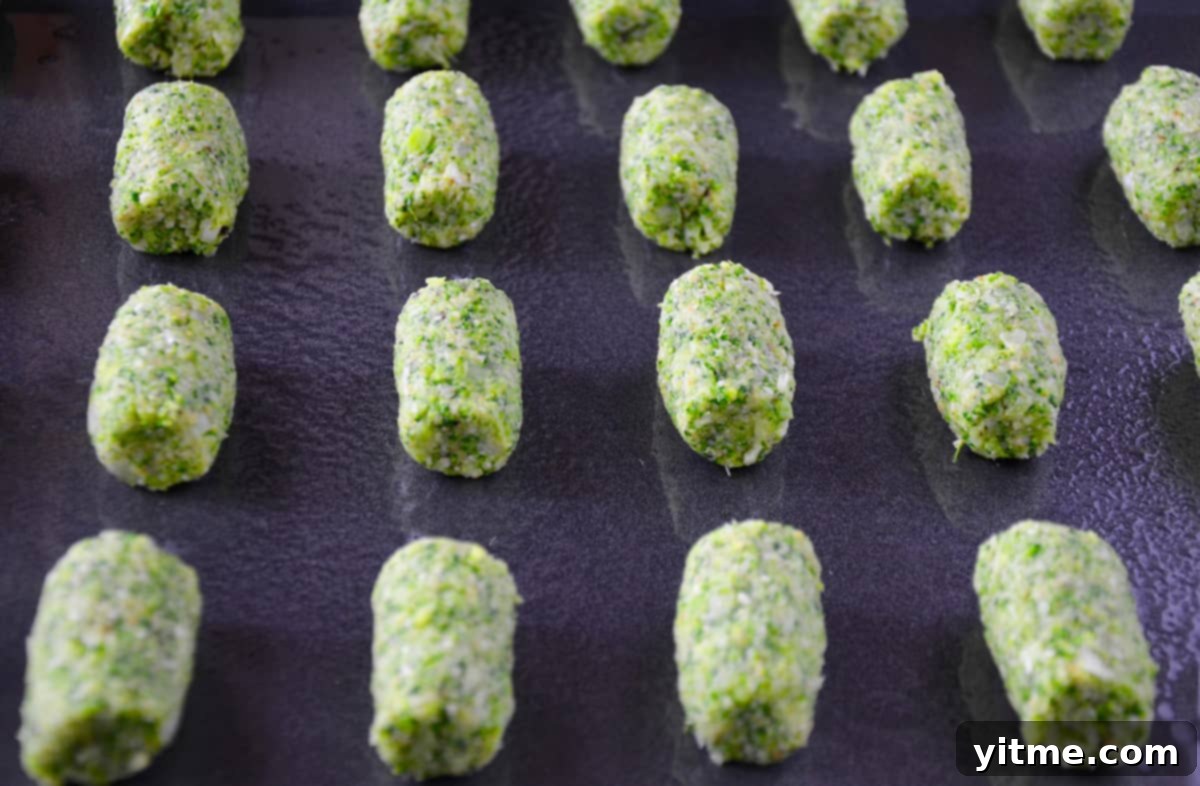 Crispy Baked Broccoli Bites 5 Unbaked broccoli tots arranged neatly on a greased nonstick baking sheet, ready for the oven.